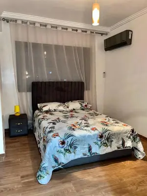 a bed with a floral comforter in a bedroom at Bel Appartement nour 5 in Marrakech