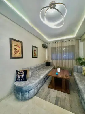 a living room with a large couch and a table at Bel Appartement nour 5 in Marrakech