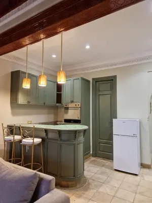 a kitchen with green cabinets and a white refrigerator at les jardins de la palmeraie 2 appart in Marrakech