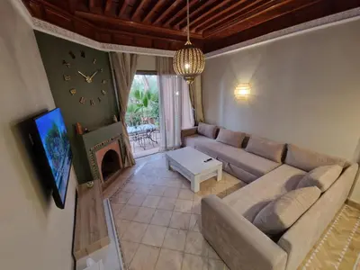 a living room with a couch and a clock at les jardins de la palmeraie 2 appart in Marrakech