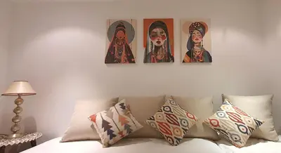 four pictures hanging on a wall above a bed with pillows at Dar Coco 180 in Marrakech