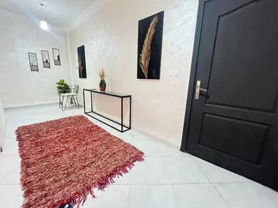 a room with a red rug and a black door at La rose à côté Carry in Marrakech
