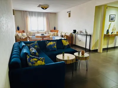 a living room with a blue couch and tables at Jardin Majorelle Appartement in Marrakech
