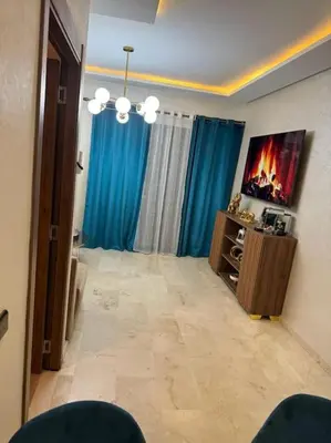 a living room with blue curtains and a flat screen tv at Appartement Haut standing in Marrakech
