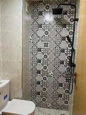 a bathroom with a toilet and a tile wall at Victorious Suites in Marrakech
