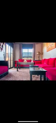 a living room with red couches and a table at Très joli appartement à Atlas Golf Resort in Marrakech