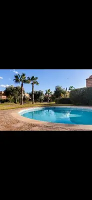 a large swimming pool with palm trees in the background at Très joli appartement à Atlas Golf Resort in Marrakech