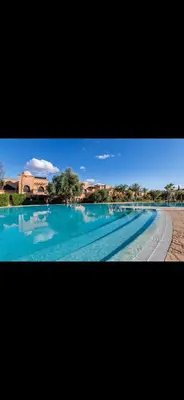 a large swimming pool with blue water in front of a building at Très joli appartement à Atlas Golf Resort in Marrakech