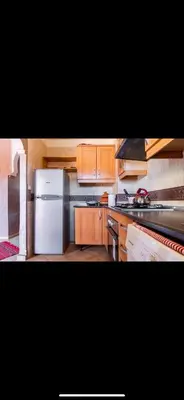 a kitchen with wooden cabinets and a white refrigerator at Très joli appartement à Atlas Golf Resort in Marrakech