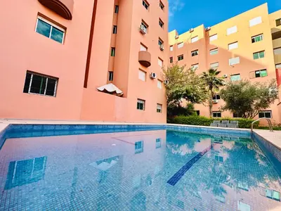 a swimming pool in front of a building at Appart F3 de luxe à Gueliz - 5 min de la gare - Piscine, WiFi, parking au coeur de Marrakech in Marrakech