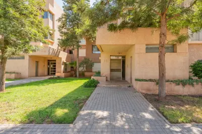 a building with trees and a sidewalk in front of it at Elegant Apartment in Prestigia Golf Marrakech in Marrakech