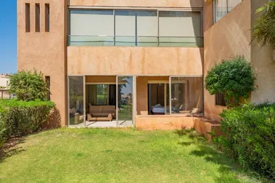 an exterior view of a house with glass windows at Elegant Apartment in Prestigia Golf Marrakech in Marrakech