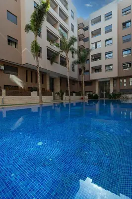 a large swimming pool with palm trees in front of a building at Menara Garden duplex 3 suites in Marrakech