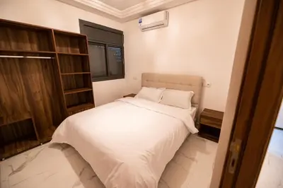 a small bedroom with a bed with white sheets at Jawhar Appart in Marrakech
