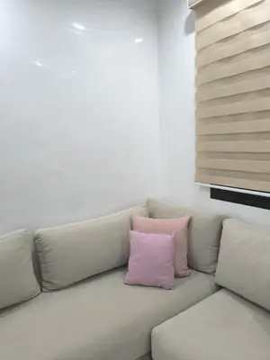 a white couch with two pink pillows on it at Appartement Piscine à Marrakech in Marrakech