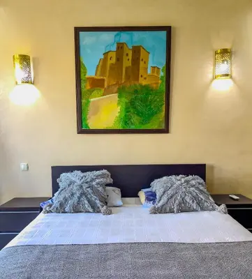 a bedroom with a bed with a painting on the wall at Rare ! duplex avec vue sur les toits de Marrakech in Marrakech