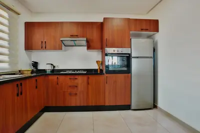 a kitchen with wooden cabinets and a stainless steel refrigerator at Best Apartment Marrakech G35 in Marrakech