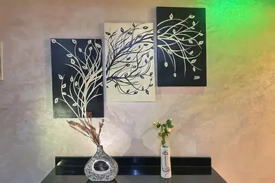 three paintings on a wall with a vase on a table at Stylish & Comfy Appartment Haven 5 Stars Location Plaza Views in Marrakech