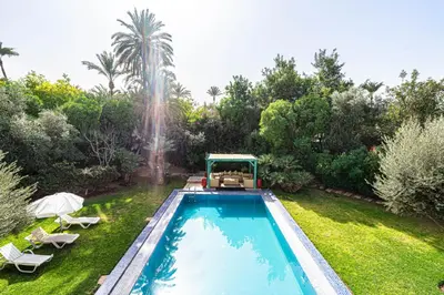 a swimming pool in a garden with a fountain at Villa palmeraie marrakech in Marrakech