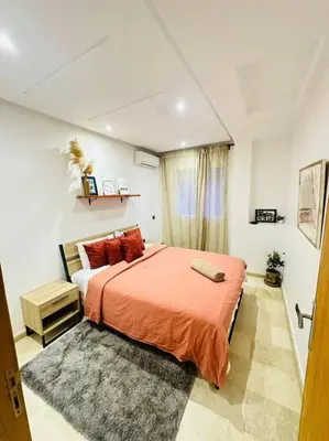 a bedroom with a bed with orange sheets and red pillows at Cosy House Marrakech Semlalia - Gueliz Center in Marrakech