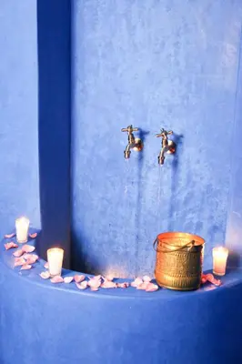 a blue wall with two birds in the air and candles at Riad Goloboy in Marrakech