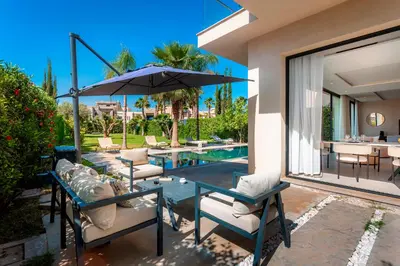 a patio with chairs and an umbrella and a pool at Villa Argana moderne et luxueuse piscine chauffée in Marrakech