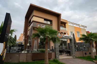 a building with a palm tree in front of it at Jawhar Appart A3 in Marrakech