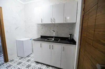 a white kitchen with a sink and a refrigerator at Jawhar Appart A4 in Marrakech