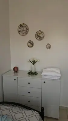 a white dresser with a vase of flowers on a wall at Portes de Marrakech in Marrakech