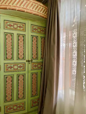 a green cabinet with a window next to a curtain at Riad La Calèche in Marrakech