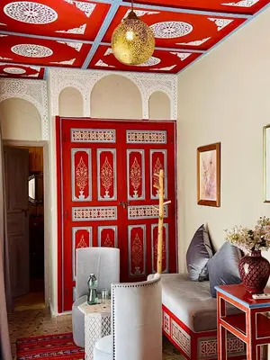 a living room with a red wall and a couch at Riad La Calèche in Marrakech