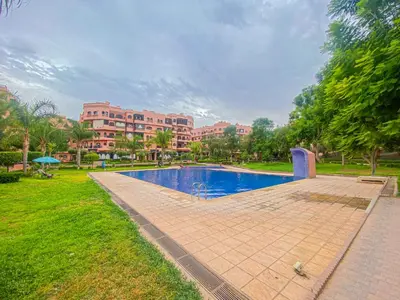a swimming pool in a park with buildings in the background at Hamza Immobiler in Marrakech