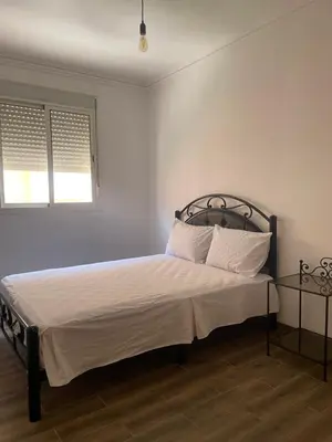 a bedroom with a bed with white sheets and a window at Issam appart in Marrakech