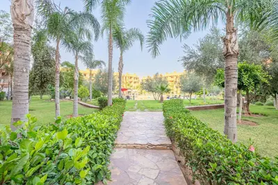 a path through a park with palm trees at Appartement cosy Piscine et chill in Marrakech