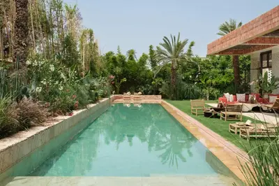 a swimming pool in a garden with chairs and a patio at Villa Saman in Marrakech