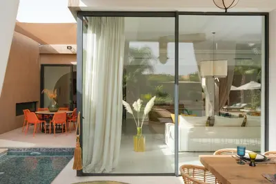 a living room with glass doors and a dining room at Villa Netumia in Marrakech