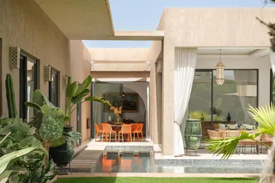 a house with a patio with a table and chairs at Villa Netumia in Marrakech