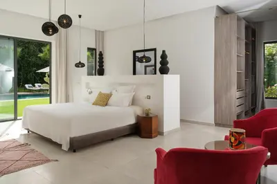a bedroom with a white bed and red chairs at Villa Netumia in Marrakech