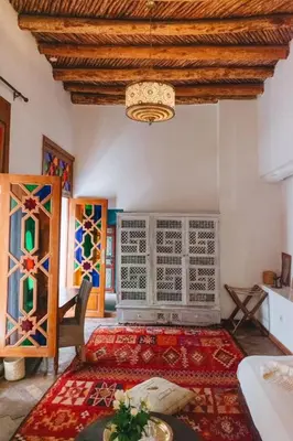 a living room with a chandelier and a rug at Boutique Hotel Riad Almoulouk in Marrakech