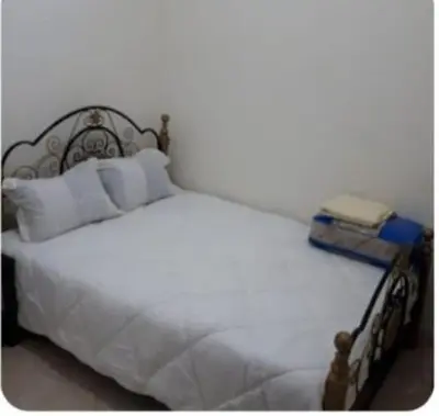 a white bed with white pillows and a book on it at Maison D'hôte Dar ALBIDAWI in Marrakech