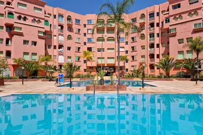 a swimming pool in front of a pink building at Best location new appart hivernag Pool FreeParking in Marrakech