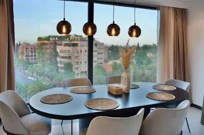 a dining room with a table and a large window at Appartement De Luxe à Marrakech avec jacuzzi piscine et vue panoramique in Marrakech