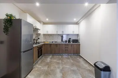 a kitchen with a stainless steel refrigerator and wooden cabinets at Family appartment Palmeraie Gate with pool in Marrakech