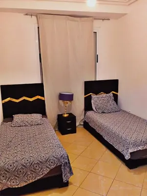 a bedroom with two beds and a lamp in it at Appartement calme et spacieux in Marrakech