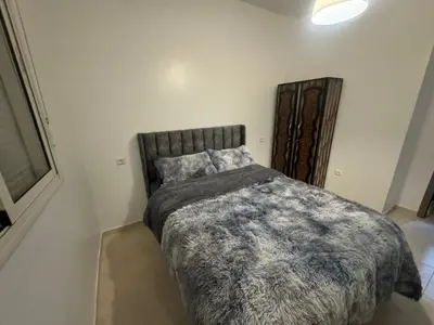a bedroom with a bed with a gray comforter at Joli appartement nouveau Rez-de-chaussée in Marrakech