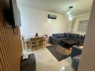 a living room with a blue couch and a table at Joli appartement nouveau Rez-de-chaussée in Marrakech