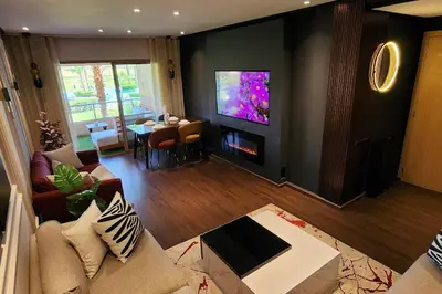 a living room with a couch and a flat screen tv at Appartement Central, vue Piscine-Golf, Lac et Montagne de L'atlas in Marrakech