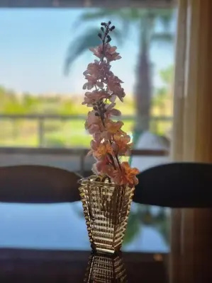 a vase with flowers in it sitting on a table at Appartement Central, vue Piscine-Golf, Lac et Montagne de L'atlas in Marrakech
