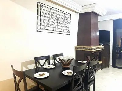 a dining room with a black table and chairs at Appartement impeccable en plein de centre ville in Marrakech