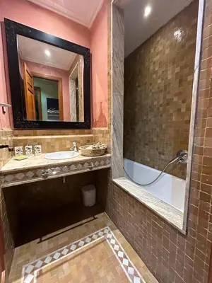 a bathroom with a tub and a sink and a mirror at Appartement au palmeraie Marrakech in Marrakech